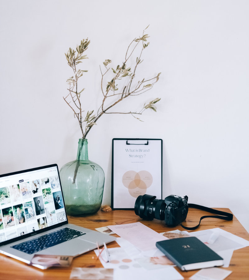 laptop,papieren over branding strategy en fotocamera op houten tafel